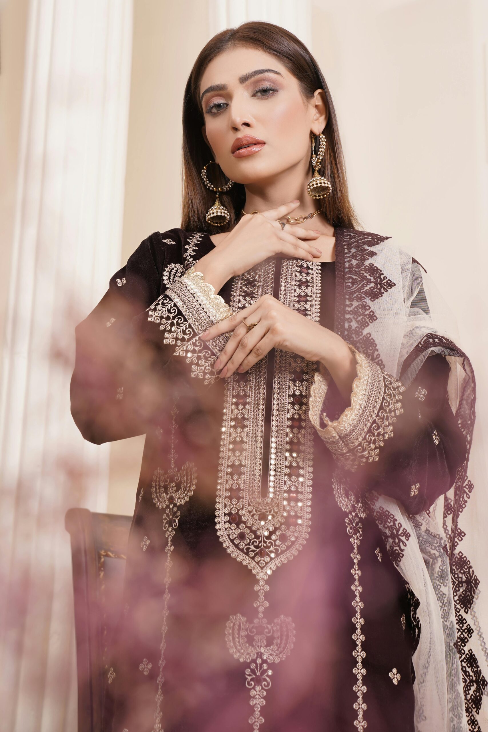 Stylish portrait of a woman in embroidered Pakistani attire, showcasing luxury fashion indoors.